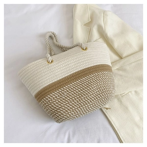 Detailed shot of beige woven tote with cotton handles and metal rings on a bed