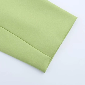 Gros plan d'un tissu de costume vert clair montrant la texture du tissage sergé