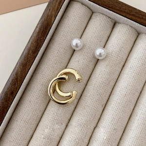 Macro shot of gold C-shaped clip-on earrings and white pearl studs in jewelry box