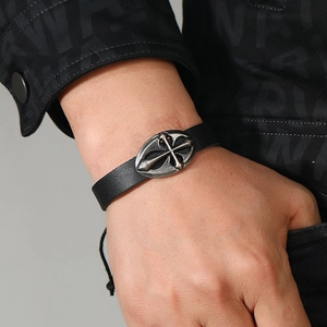 Close-up of vintage braided leather bracelet featuring a silver-toned cross emblem for men