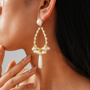 Macro view of vintage baroque teardrop pearl earrings worn on model for detail
