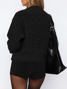 Detail view of the back of a black long-sleeved knit sweater and black leather shoulder bag