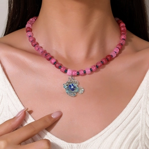 Collana di perline regolabile con perle rosa e ciondolo a forma di pesce blu indossata da modella