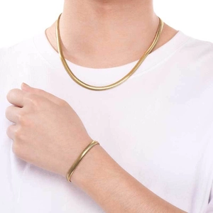 Primo piano di una modella che indossa un set di collana e bracciale a catena piatta oro