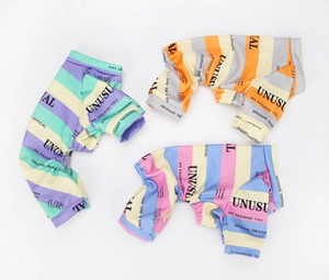 Flat lay of colorful striped dog pajamas in mint, orange, and pink knit cotton fabric