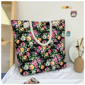 Detail of colorful rose floral print on black canvas tote bag with thick cotton rope handles