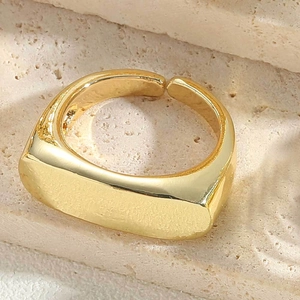 Macro view of a gold-plated signet ring with a smooth rectangular face and open design