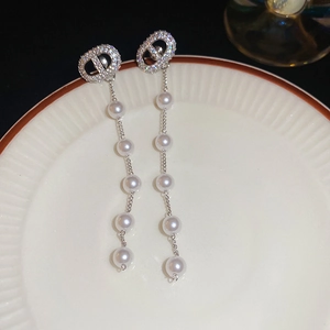 Detail of silver drop earrings with CD logo crystals and hanging white pearls