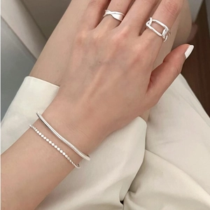 Close-up of S925 sterling silver beaded bracelet and geometric rings set on wrist