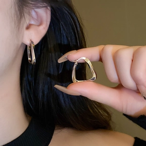Macro shot of silver geometric trapezoid hoop earrings with smooth polished finish