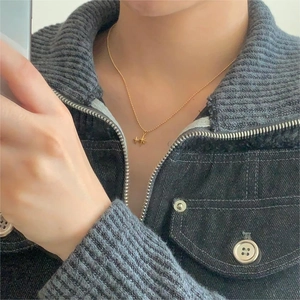 Detail of a minimalist gold starburst pendant necklace worn by a fashion model