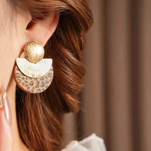 Close-up of geometric earrings with leopard print and gold discs on model