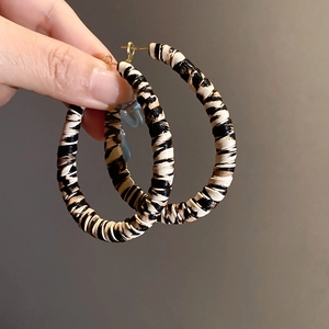 Detail shot of large C-shaped hoop earrings featuring black and white striped fabric texture