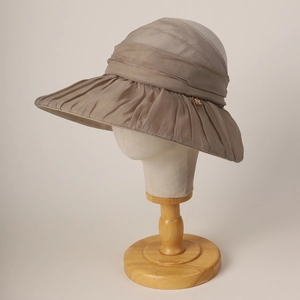 Close-up of elegant wide-brim mesh sun hat with pleated texture and gold accent