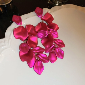 Detail of rose red layered flower petal tassel earrings on a textured white plate