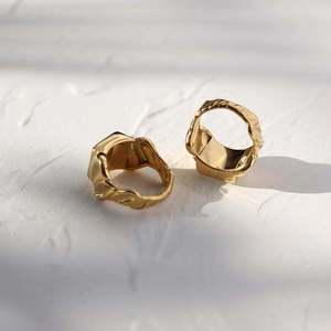Macro detail of golden 18K gold plated wide rings with wavy texture and geometric design