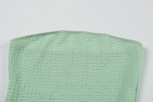 Détail de la texture smockée vert clair avec des coutures soignées sur l'ourlet