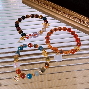 Detailed view of layered gemstone bracelets with tiger eye, agate, and pearl pendants