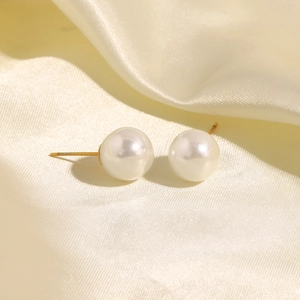 Close-up of large white pearls on elegant beige silk fabric with gold post details