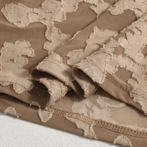 Détail macro du tissu jacquard floral 3D marron sur la robe à manches longues