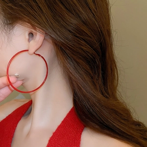 Close-up of minimalist large red hoop earrings with polished finish on model's ear