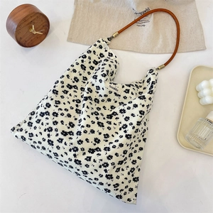 Gros plan d'un sac cabas en toile fleurie avec anses en cuir et étiquette de marque