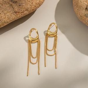 Detail of gold geometric tassel earrings set against natural stones for a luxury look