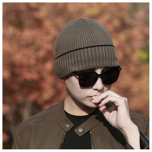 Detail of dark brown ribbed knit beanie featuring black stripe accent and warm texture
