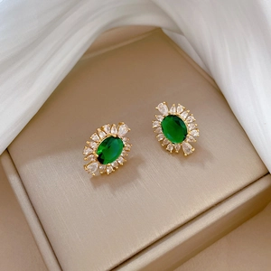 Detail view of gold stud earrings with green oval stone and white marquise crystals