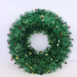 Close-up of green tinsel Christmas wreath with red and gold sequins for festive decor