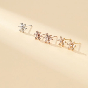 Detailed view of zircon snowflake earrings in silver, gold, and rose gold finishes