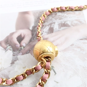 Detail of pink leather woven gold chain strap with adjustable engraved metal ball buckle