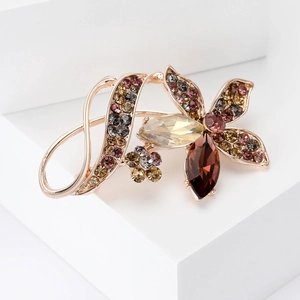 Macro shot of gold-plated flower brooch with champagne and amber rhinestones detail