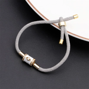 Detailed macro of grey braided cord bracelet with gold evil eye charm and crystal accents