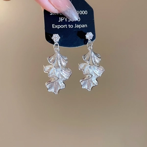 Detail showing silver ginkgo leaf earrings with crystal stud on display card