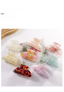 Detailed overhead shot of 8-piece assorted colorful acetate hair claws on a wooden tray