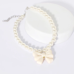 Close-up of pearl pet necklace with cream bow pendant and adjustable metal chain link