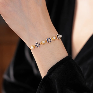 Detailed view of vintage flower bracelet with white pearls and navy blue gemstones on wrist
