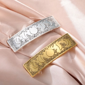 Detail of vintage metal hair clips with embossed forest and moon phase patterns