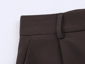 Détail du pantalon marron foncé montrant la taille, les passants et les poches de près