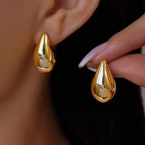 Detailed close-up showing a gold water drop earring on a model with glossy metal finish