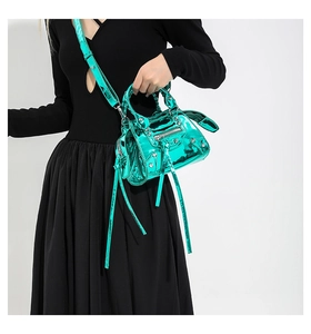 Detail of bright green patent leather motorcycle bag featuring metallic rivets and tassels
