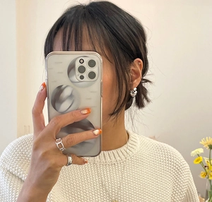 Close-up of polished silver twisted earrings and rings shown in a mirror selfie lifestyle shot