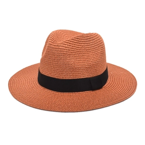 Detail of woven straw fedora hat in reddish brown with a classic black ribbon band