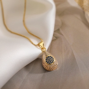 Water drop gold pendant necklace with blue zircon inlay on elegant silk background