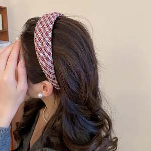Detail view of red and white checkered fabric headband on model with elegant jewelry