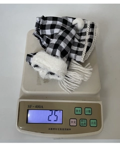Detailed view of plaid Christmas bottle cover with white lace trim and pom-poms on scale