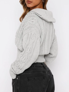 Dettaglio della maglia a trecce grigia e del comodo cappuccio su un maglione da donna