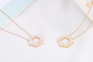 Macro detail of rose gold and gold hexagonal honeycomb necklaces with sparkling crystals