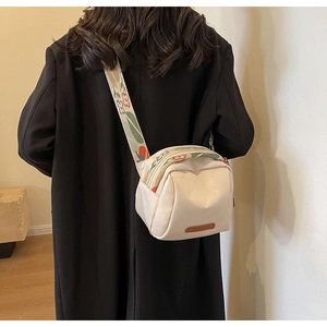 Dettaglio della borsa a tracolla bianco sporco con ampia tracolla a fiori colorati